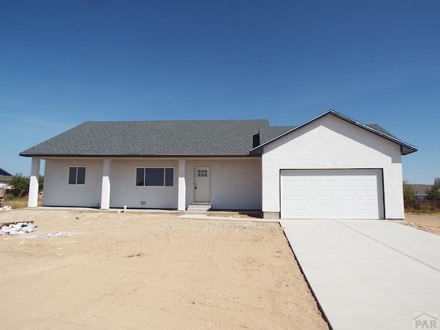 ranch-style home featuring a garage, driveway, a shingled roof, and stucco siding