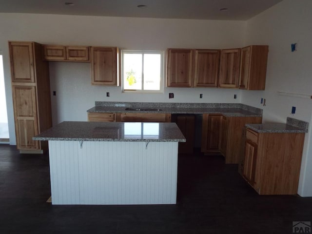 kitchen featuring dark wood-style floors, a kitchen bar, brown cabinetry, and a center island