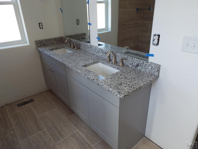 bathroom with double vanity, a sink, and wood tiled floor