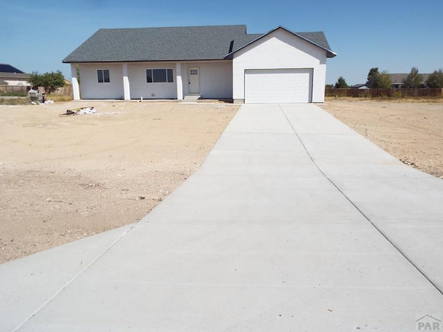 single story home featuring concrete driveway, an attached garage, and stucco siding