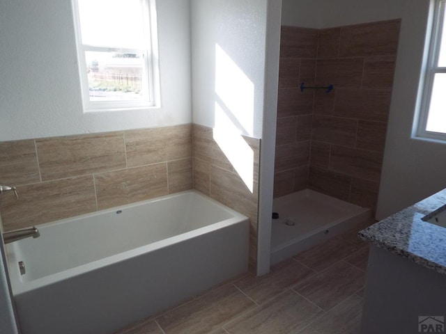 full bathroom with a tile shower, a garden tub, and vanity