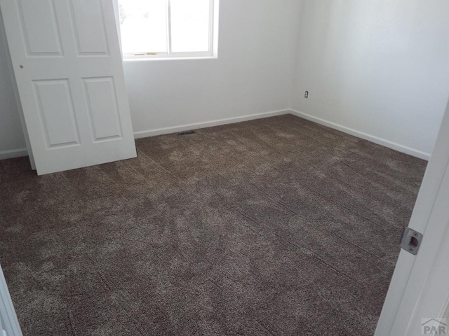 unfurnished bedroom with dark colored carpet and baseboards