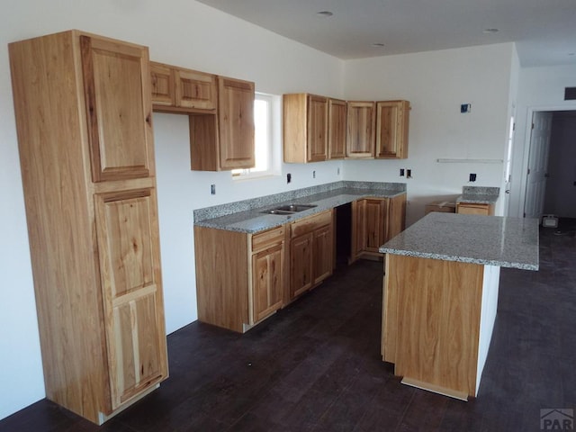 kitchen with dark wood-style floors, a sink, a kitchen island, and light stone countertops