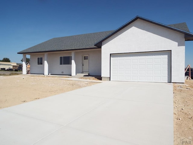 single story home featuring a garage, concrete driveway, roof with shingles, and stucco siding