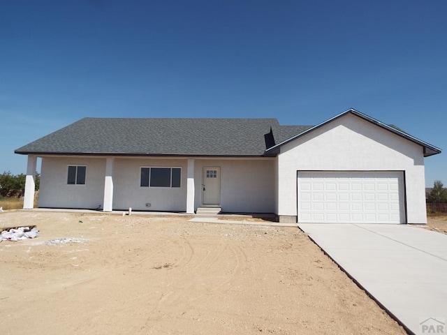 single story home featuring driveway, an attached garage, and stucco siding