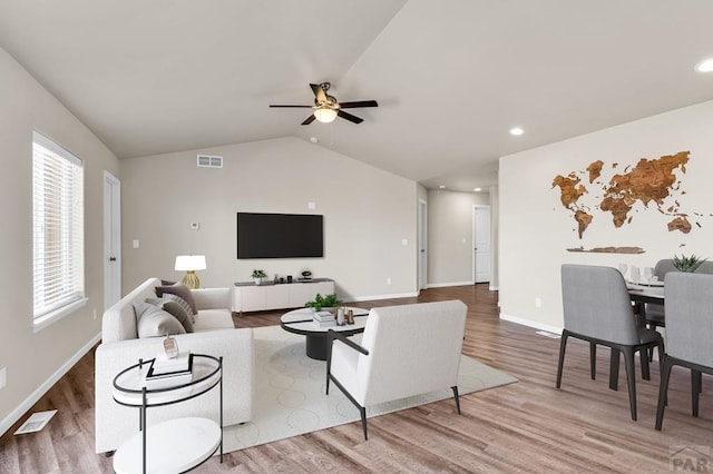 living room featuring lofted ceiling, visible vents, ceiling fan, wood finished floors, and baseboards