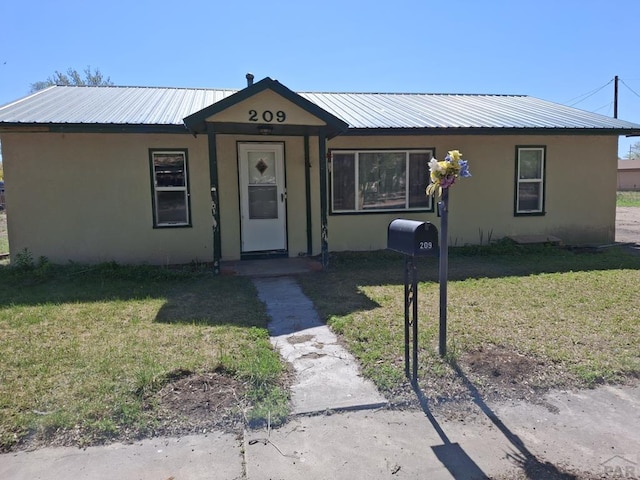209 5th St, Fowler, CO 81039 - view of front of property with stucco siding, a front yard, and metal roof