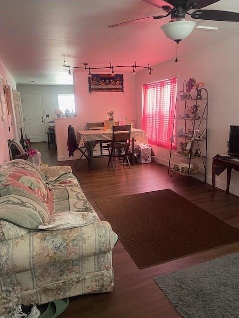 living area featuring dark wood-style floors, baseboards, and a ceiling fan