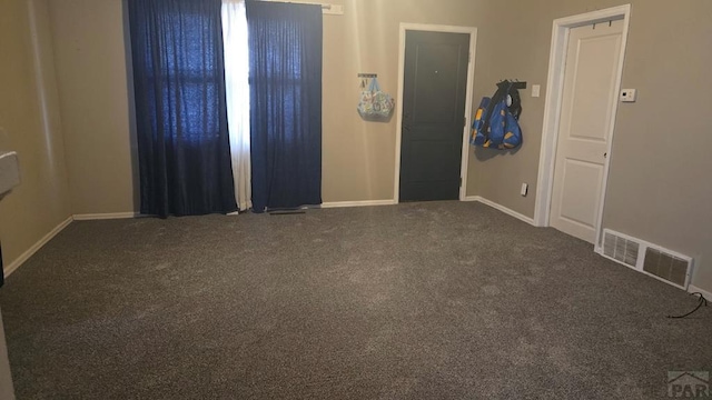 spare room with carpet flooring, baseboards, and visible vents