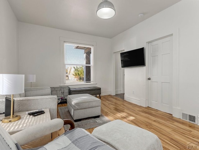 living area featuring light wood-style flooring, visible vents, and baseboards