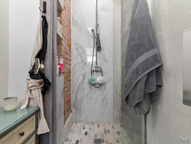 full bath with a marble finish shower and vanity