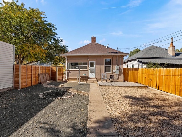 rear view of property with a fenced backyard, a patio, a chimney, and roof with shingles