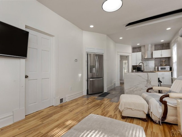 living room featuring light wood-style flooring, baseboards, and recessed lighting