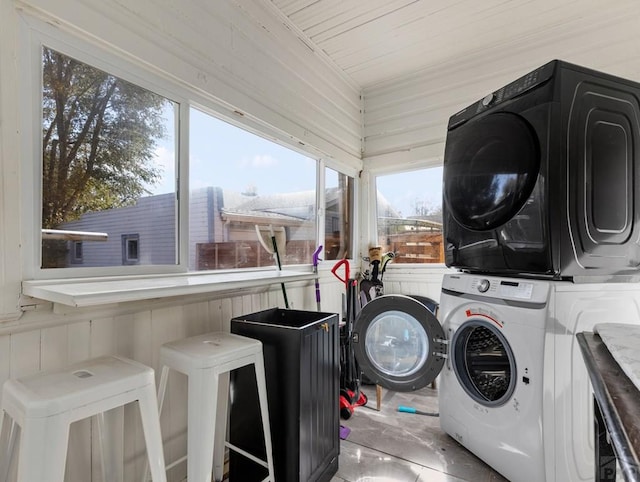 washroom featuring laundry area, wooden walls, and stacked washer and clothes dryer