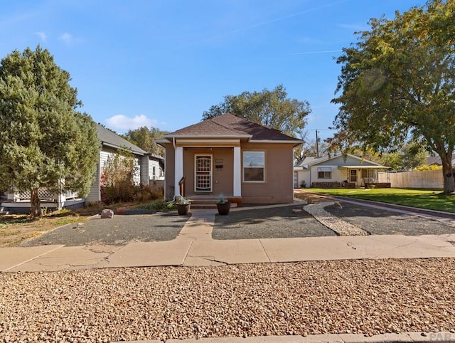 bungalow featuring fence and stucco siding