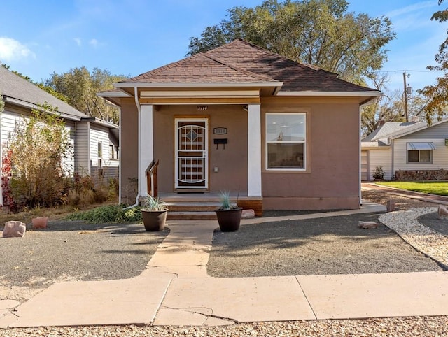 bungalow featuring roof with shingles and stucco siding