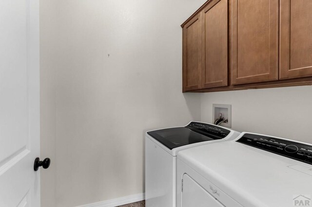 washroom featuring cabinet space, baseboards, and independent washer and dryer