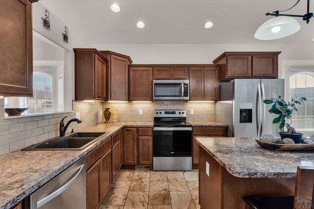 kitchen featuring appliances with stainless steel finishes, a wealth of natural light, a sink, and backsplash