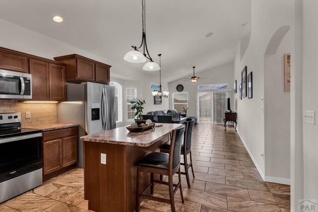 kitchen with a center island, stainless steel appliances, hanging light fixtures, open floor plan, and a kitchen breakfast bar