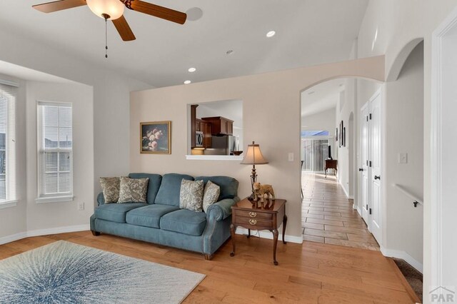 living room with light wood-type flooring, arched walkways, a healthy amount of sunlight, and recessed lighting