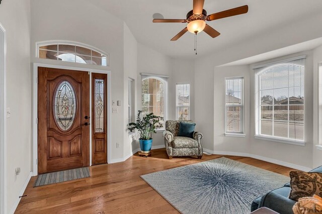 foyer with vaulted ceiling, wood finished floors, a ceiling fan, and baseboards