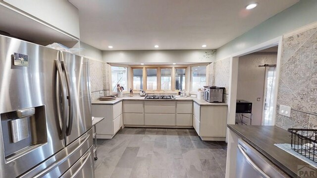 kitchen featuring white cabinets, modern cabinets, stainless steel appliances, light countertops, and recessed lighting