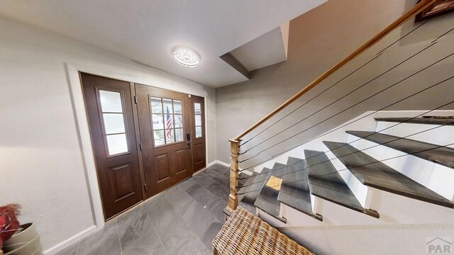 foyer featuring baseboards and stairs