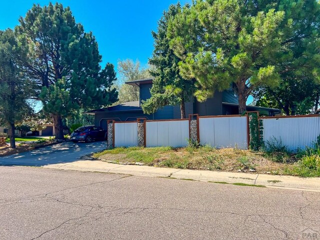 view of side of property featuring aphalt driveway and a fenced front yard