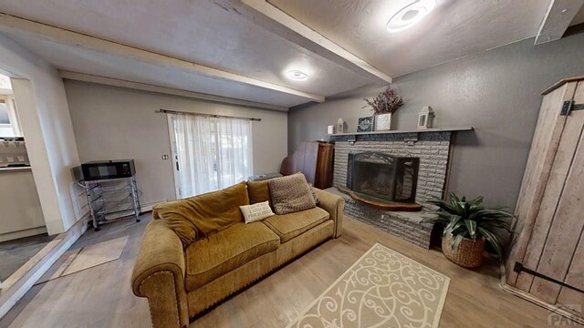 living room with light wood-type flooring, a fireplace, and beam ceiling