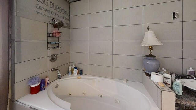 full bath featuring a tub with jets and tile walls