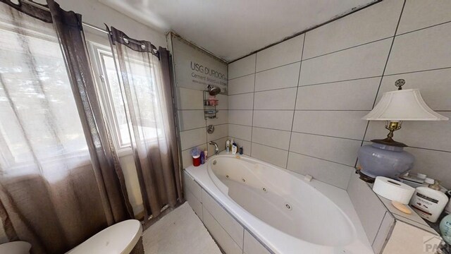 bathroom featuring a combined bath / shower with jetted tub and tile walls