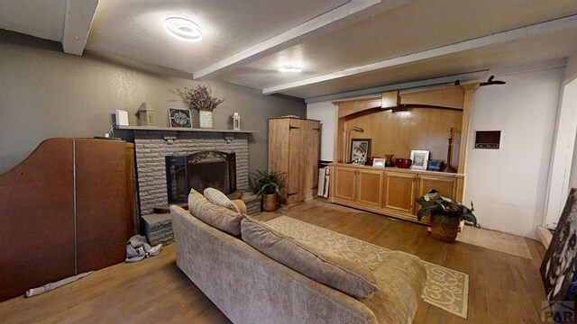 living area featuring a brick fireplace, light wood-style flooring, and beam ceiling