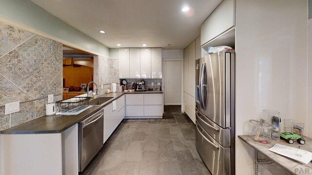 kitchen with tasteful backsplash, dark countertops, recessed lighting, appliances with stainless steel finishes, and white cabinetry