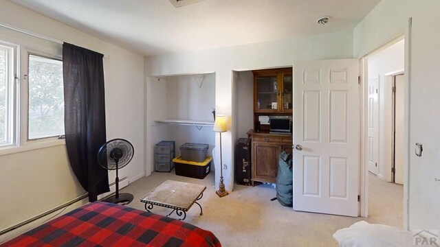 bedroom with a baseboard heating unit and light carpet