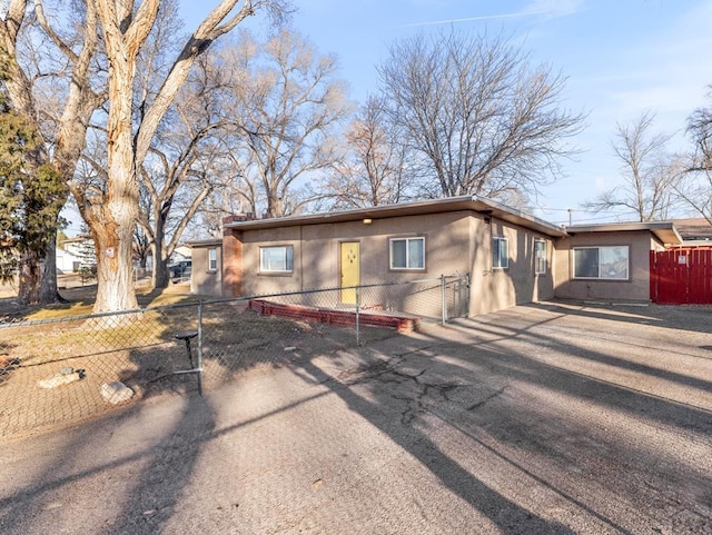 ranch-style house with aphalt driveway, fence, and stucco siding