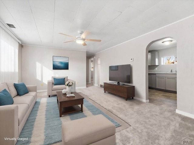 living room featuring arched walkways, light colored carpet, plenty of natural light, and visible vents