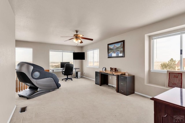 office space with baseboards, visible vents, light colored carpet, ceiling fan, and a textured ceiling