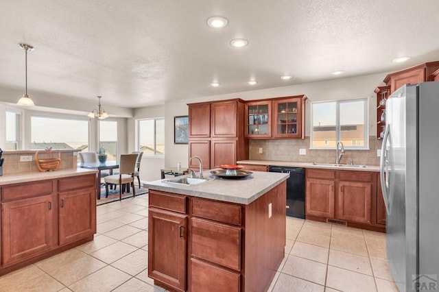 kitchen with black dishwasher, a center island with sink, a sink, and freestanding refrigerator