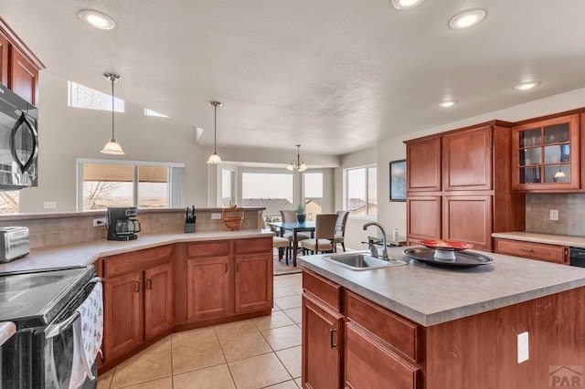 kitchen featuring black microwave, hanging light fixtures, tasteful backsplash, and a sink