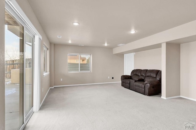 living area featuring a healthy amount of sunlight, light carpet, and baseboards