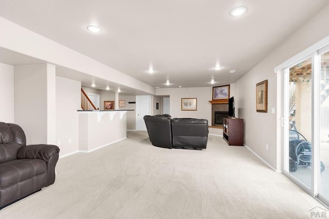 living area featuring a tile fireplace, recessed lighting, light carpet, baseboards, and stairs