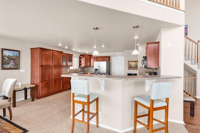 kitchen featuring appliances with stainless steel finishes, brown cabinets, a peninsula, and a kitchen breakfast bar