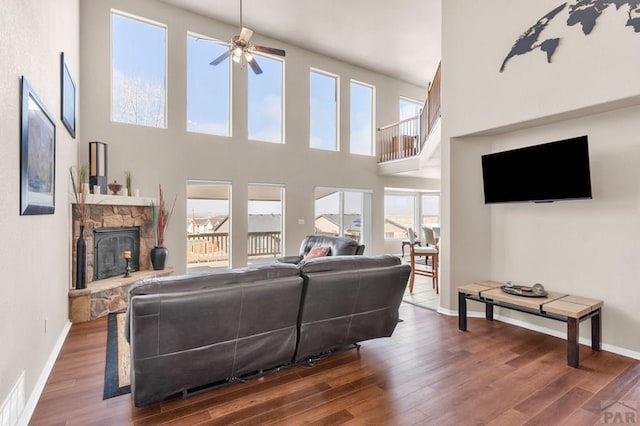 living area featuring a fireplace, baseboards, and wood finished floors