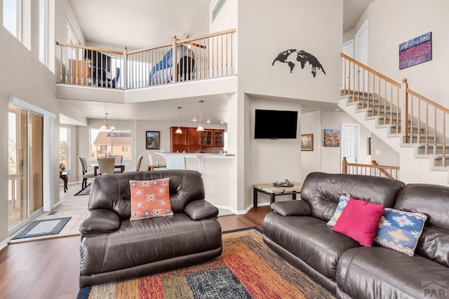 living area with stairs, a chandelier, wood finished floors, and baseboards