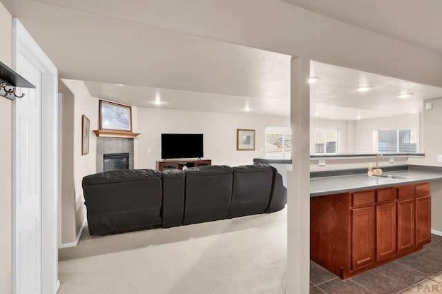 living area featuring dark tile patterned floors, a tiled fireplace, and a wealth of natural light