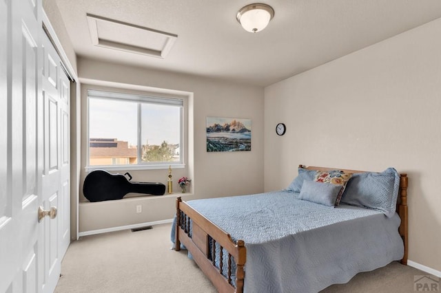 bedroom with attic access, baseboards, visible vents, light colored carpet, and a closet