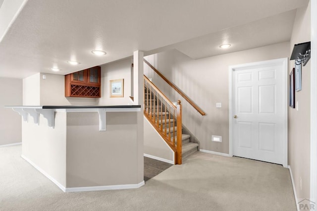 kitchen featuring carpet floors, baseboards, a breakfast bar, and a textured ceiling