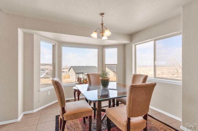 dining area with light tile patterned floors, baseboards, and a notable chandelier