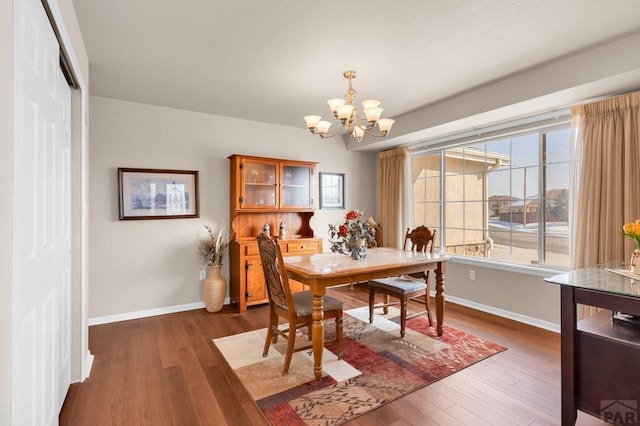 dining room with a chandelier, baseboards, and wood finished floors