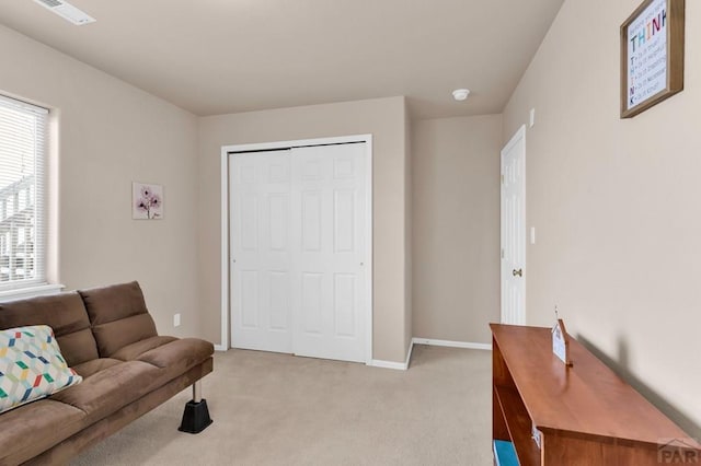 living area featuring light carpet, plenty of natural light, visible vents, and baseboards